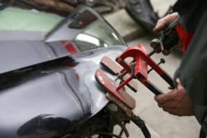 photo d'un mécanicien entrain de débosseler une voiture dans un garage à Huy