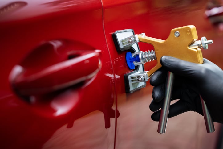 Photo d'un mécanicien entrain de débosseler une voiture à huy